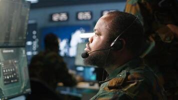 Army telecommunication systems operator using radio and satellite gear, providing combat support. Military dispatcher managing communications networks, looking at screens, camera A photo