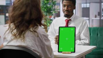 Job applicant and employer discussing in an interview with isolated mockup display on a device, high end corporate office. Businessman and HR recruiter share career development ideas. Camera A. photo