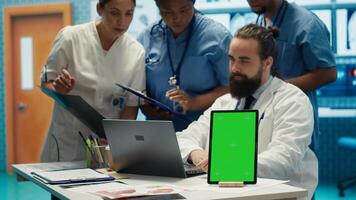Group of doctors consulting hospital records next to chroma key display, using x ray test results to examine diagnosis. Diverse experts meeting at private clinic to provide treatment plan. Camera A. photo