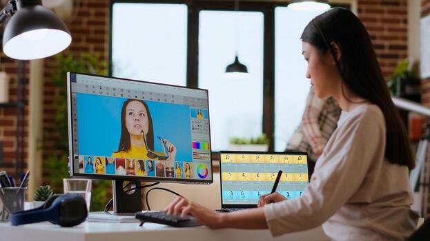 Freelance designer works on a photo editing project in a remote office, using advanced design software. Home workspace promotes creativity and innovation for online work. Camera B.
