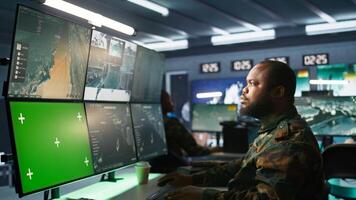 Air force officer performing tactical level surveillance in command room using mockup screen. Military specialist using radar on chroma key gear to look at assault zones, camera B photo