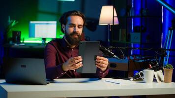 Tech expert presenting tablet in entry level low budget price range to interested viewers, filming in studio. Viral content creator reviewing digital device in front of internet audience, camera A photo