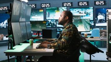 Army expert working in governmental facility operating surveillance tech, evaluating target data. Soldier doing job in HQ base of operations, engage enemy forces, camera A photo