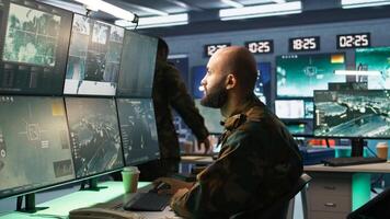 Man looking at screens in military HQ base housing operational missile defense system designed to intercept ballistic rockets. Special forces expert using tracking gear and radar systems, camera B photo