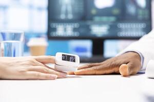 General practitioner taking the oxygen saturation and vital signs for a patient, using oximeter and other diagnostic tools in cabinet office. Male specialist consulting a woman, healthcare services. photo