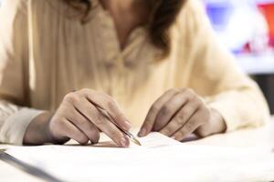Female CEO solving her business paperwork tasks and signing documents, approving requests from employees and authorizing work contracts in her high end office. Legal management. Close up. photo