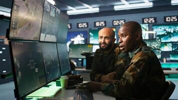 Army unit working in governmental facility next to coworker, doing brainstorming, operating surveillance tech. Team of soldiers doing job in HQ base of operations, camera B photo