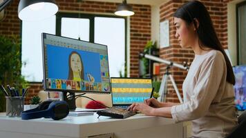 Asian creative woman edits photos using professional design software in a modern home office. Working with digital tools in the graphic design industry, retouching techniques. Camera A.