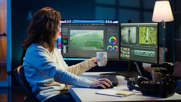 Videographer using editing software to assemble footage into cohesive final result while enjoying cup of coffee. Specialist color correcting clips while drinking hot beverage, camera A photo