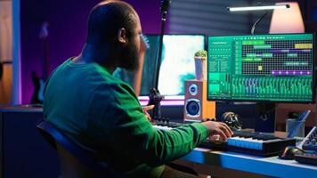 Creative songwriter recording new tracks with microphone and midi controller, playing piano notes in home studio. Skilled musician composing music with electronic keyboard and stereo gear. Camera A. photo