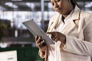 Businesswoman developing and implementing operational policies and strategic plans using tablet. Close up of manager in office managing budgets and forecasting operational needs with device photo