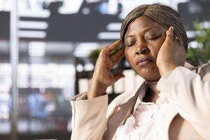 Worker in pain, suffering migraine while doing tedious data entry job, inputting data on laptop. Fatigued african american woman hurting form headache while solving tasks in office, close up photo