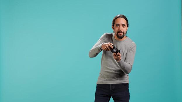 Cheerful player happy after winning gaming console game, shaking fist, studio background. Portrait of man satisfied after being victorious in videogame, defeating all enemies using gamepad, camera A photo