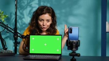 Internet show host being sponsored by partnering brand to do green screen laptop unboxing content. Tech specialist does influencer marketing, doing mockup notebook product placement, camera A photo
