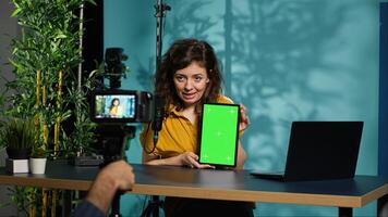 Woman holding green screen tablet, talking about specifications, filming with professional camera. Internet show host presenting chroma key device features, recording with filming gear, camera A photo
