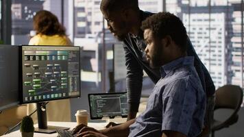 Developer working together with helpful colleague on artificial intelligence machine learning tech, improving company systems. IT specialist assisted by coworker to compare data photo