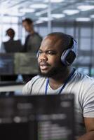 Engineer in data center listening music, optimizing IT infrastructure using network management skills. Server room expert wearing headphones upgrading gear, reducing operational costs photo