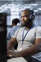 Technician listening music, using machine learning applications to optimize server farm operations. IT expert waring headphones hearing podcast while implementing server virtualization in data center photo