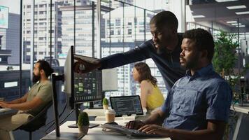 Admin assisted by coworker, working with machine learning artificial intelligence critical to autonomous systems. IT staff members working together to transform data into predictive models, camera B photo