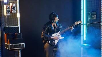 Female rock star singing a heavy metal song while playing her guitar for a music performance on stage. Loud edgy performer captivating the crowd with her iconic rebellious style. Camera B. photo