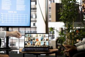 Team of office clerks looking over revenue figures on documents in office during teleconference meeting. Staff members comparing company statistical numbers during remote videocall photo
