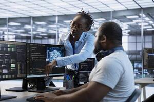 Manager showing engineer how to finish tasks in data center providing resources for different workloads. Team leader teaching IT specialist how to monitor supercomputers, pointing to screen photo