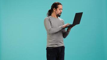 Man composing email, typing on laptop keyboard, excited to log off after work. Cheerful person sending mail online, brainstorming message idea, isolated over studio background, camera A photo