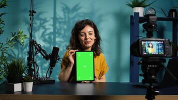 Woman filming tech tutorial on how to repair damaged mockup tablet using professional camera. Engineer teaching fans to install operating system on green screen device, recording with gear, camera B photo