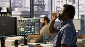 System administrator in office yawning during shift, feeling tired while looking at software interface on PC. Exhausted man being sleepy in workspace, programming on computer monitor, camera A photo
