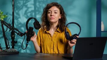 Audio technician presenting professional headphones in different price ranges to audience, comparing them to find winner. Expert recommending listening devices to fans, doing review, camera A photo