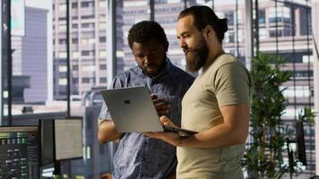 IT employees in office working together using laptop, testing and deploying programs and systems. Developer and colleague checking code on notebook, doing brainstorming in workspace, camera A photo