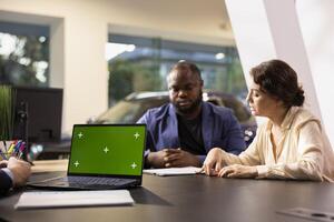 Sales executive in dealership using isolated screen laptop, negotiating price and extra car features to help solidify deal. Agent persuading hesitant customers to buy vehicle using chroma key notebook photo