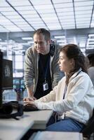 Manager checking project progress of technician programming in AI data center used for machine learning training. Team leader supervising worker coding artificial intelligence tech photo