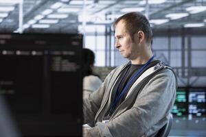 Software developer in server farm ensuring compliance with industry standards and regulatory requirements. Data center IT expert conducting security audits to protect against vulnerabilities photo
