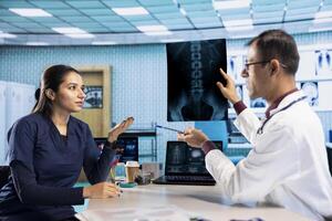 Healthcare provider presenting lab test results to a patient in office, reviewing x ray results and doing a scan interpretation. Medical technology for diagnostics and care management. photo