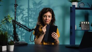 Tech guru presenting tablet from brand sponsoring , urging viewers to purchase it. Technology expert does influencer marketing by advertising digital device to audience, camera B photo