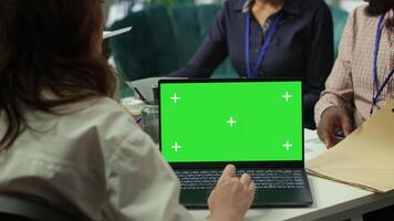 Diverse team of business associates looking at mockup chroma key screen during executive board meeting, utilizing smart technology. Enterprise staff develop effective business strategies. Camera A. photo