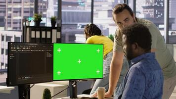 Admin doing software debugging on green screen PC, asking for help from coworker, checking errors in code. Worker fixing coding mistakes on mockup computer, being assisted by colleague, camera A photo
