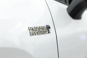 Logo of plug in hybrid electric vehicle using batteries and fuel to power electric motor, producing lower levels of emissions. EV car with rechargeable battery from external power source, close up photo