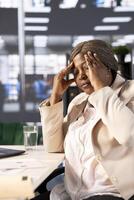 Aching CEO suffering migraine at work while using laptop to identify opportunities for cost savings and operational enhancements. Ill manager hurting, feeling sick while at computer desk photo