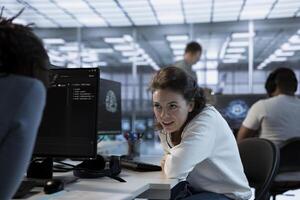 Joyous technician chatting with colleague while doing maintenance on artificial intelligence neural networks. Smiling admin talking with coworker while using AI systems aiding processing photo