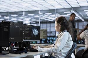 Engineer doing job shift in AI server hub used for processing vast amounts of data. Artificial intelligence programmer at work in data center, sitting at PC desk, typing on keyboard photo