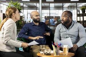 Manager yelling at employees during briefing meeting, unhappy with their ideas for profit growth presented. Angry director berating workers in office for not understanding startup evolution vision photo