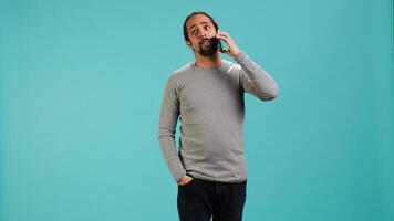 Man discussing with best friend over telephone call using smartphone, studio backdrop. Person talking with mate in phone call using cellphone, isolated over studio background, camera A photo