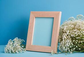 Wooden frame with baby's breath on blue background photo