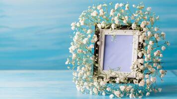 Photo frame with lily of the valley flowers on blue background