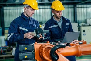 Engineers working with robotic automation technology in a modern factory setting during the day photo