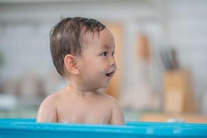 Joyful toddler enjoying bath time in a colorful tub at home while exploring water photo