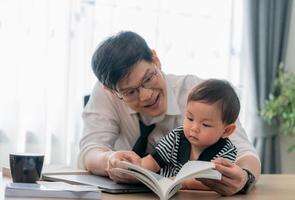 Father shares a reading moment with his young child at home during a sunny afternoon photo