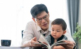 Father reads to toddler in cozy indoor space with plants and natural light photo